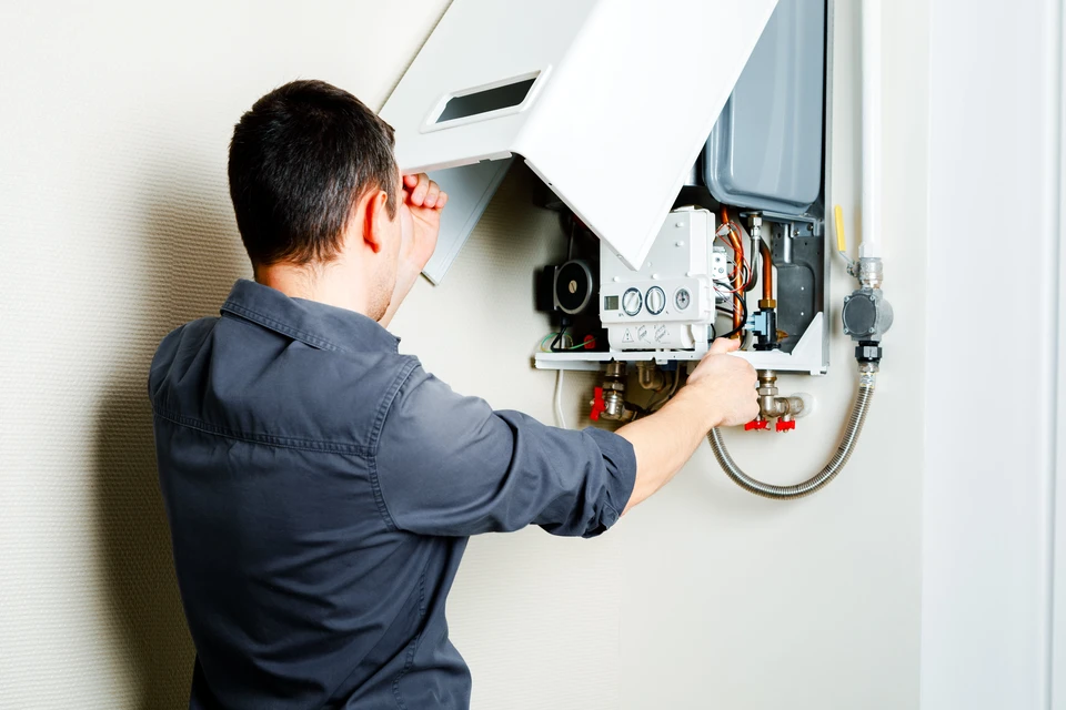 Technicien en plomberie chauffage installant un radiateur à ailettes blanches dans un intérieur résidentiel